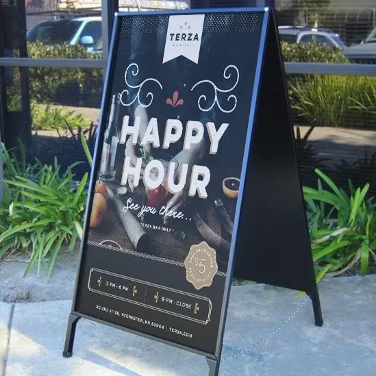 A chalkboard A-frame on the sidewalk announcing Terza’s happy hour