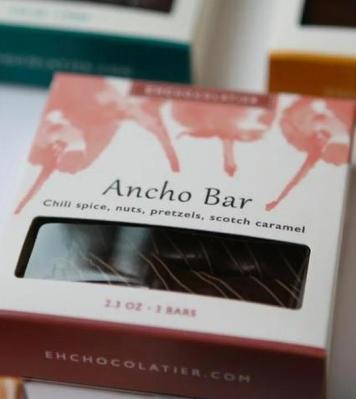 The Ancho Bar box up close: terracotta brushwork, the flavor name and descriptor, and the bar visible through the window