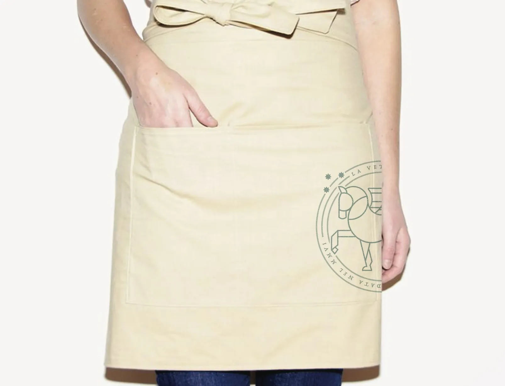A cream La Vetta service apron, the winged-horse seal printed at the hip