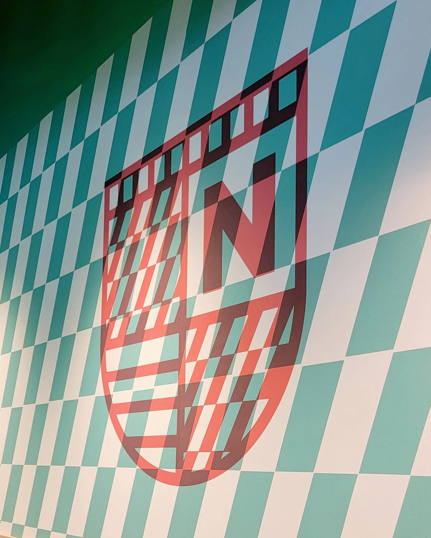The Pizza Novara N badge on a wall of teal and white checkerboard tile