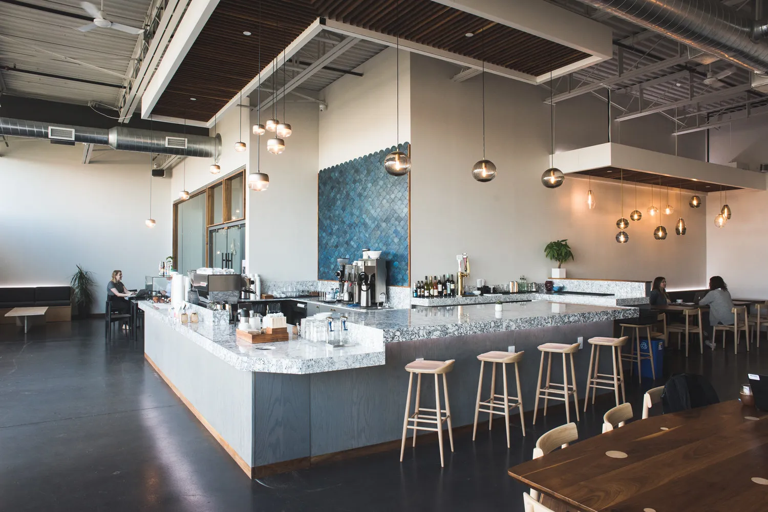 The Parallel Cafe bar: a long marble counter under pendant lights, stools along its length, the room bright with high windows