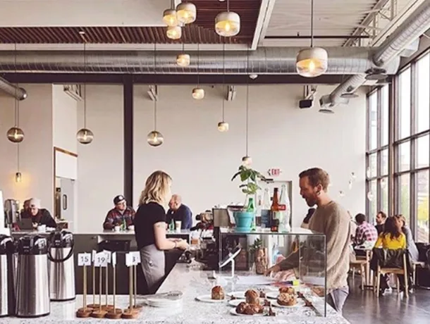 A barista helping a customer at the Parallel bar, the room bright behind them