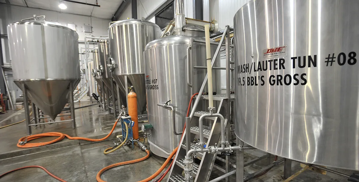 Stainless tanks in the River Falls brewhouse — the mash and lauter tun stencilled with its number