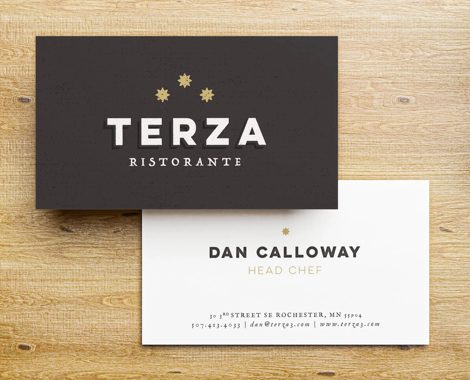Terza business cards on wood, the gold wordmark on dark brown over a white contact card