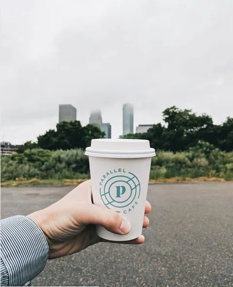 A Parallel cup held up against the Minneapolis skyline
