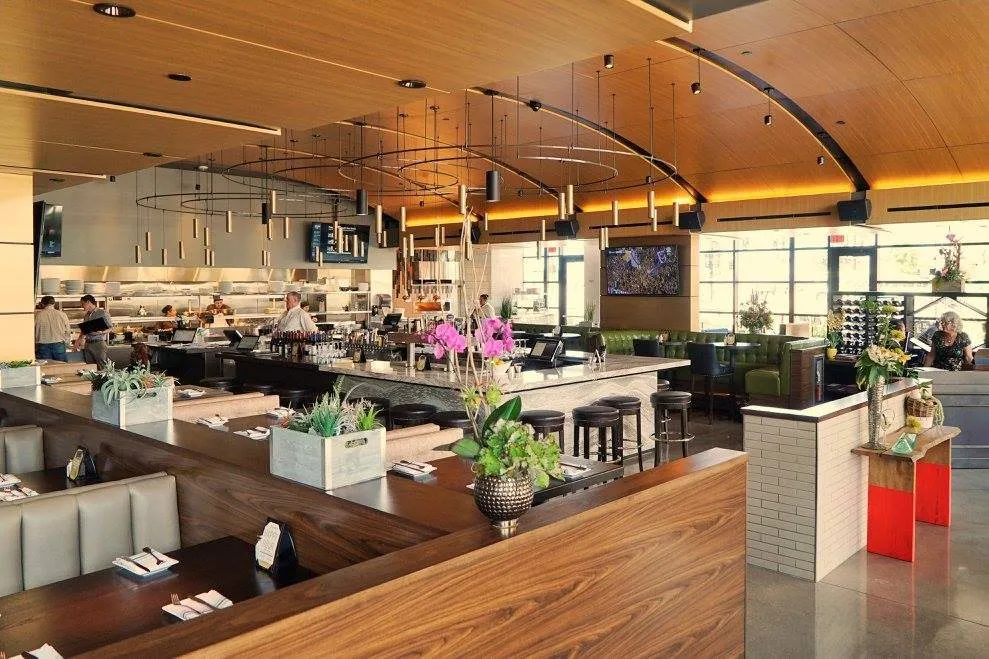 The Hazelwood dining room and bar under a curved wood ceiling, open to the windows