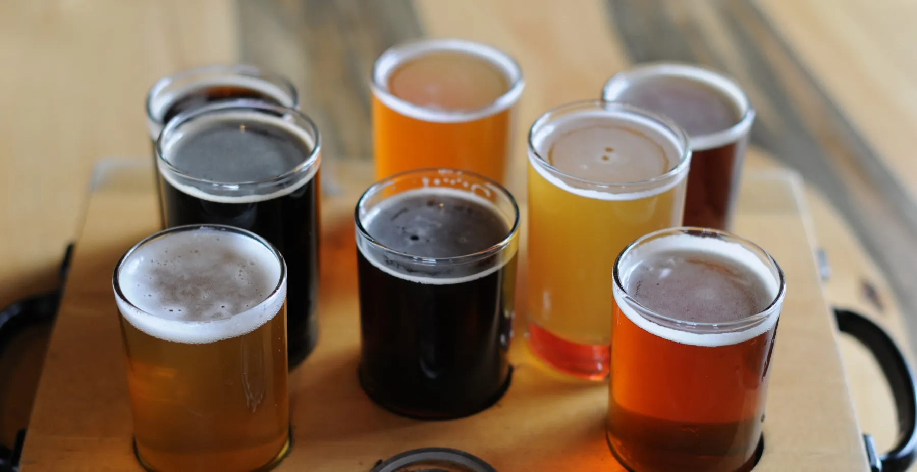 A tasting flight on the taproom bar, six glasses from pale gold to black