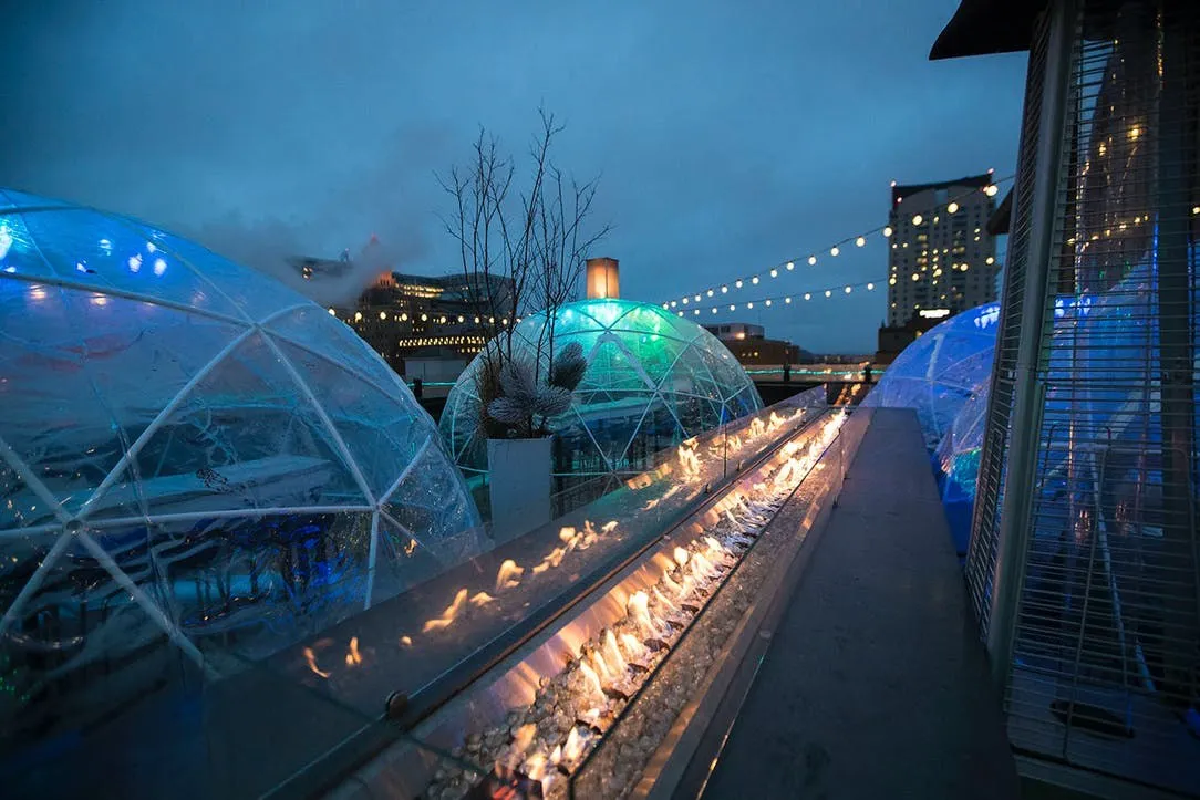 Lit geodesic igloos set along the rooftop in winter — an activation the operator introduced later, after the identity work