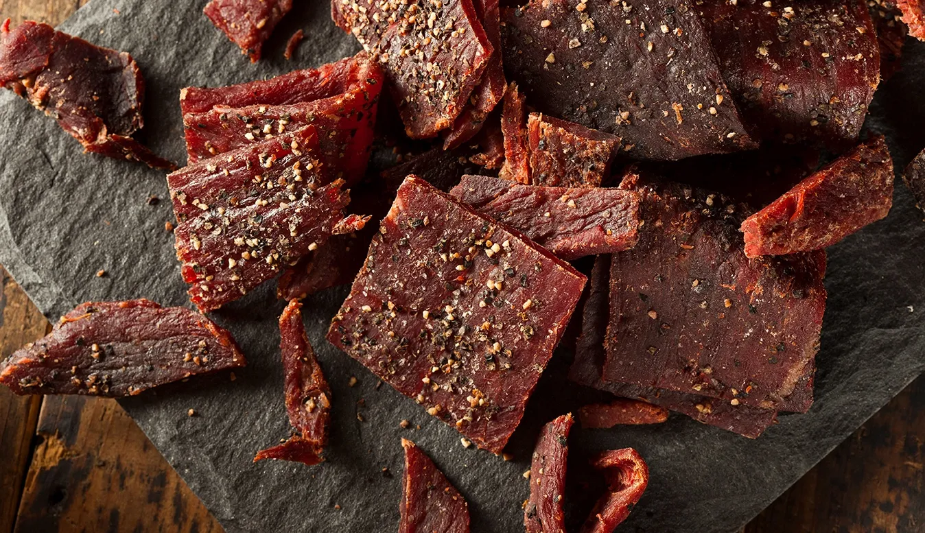 Peppered beef jerky on slate, cut into strips