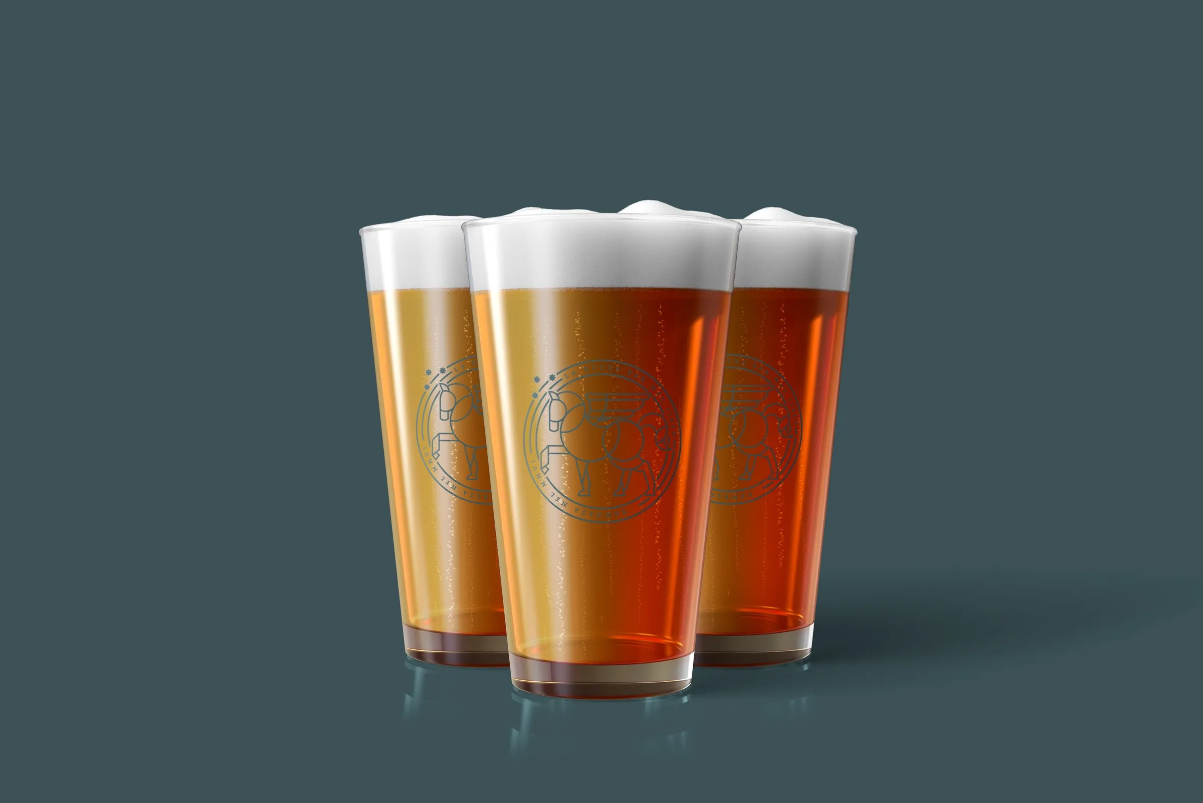 Three filled La Vetta pint glasses, the seal etched on each, against blue-green