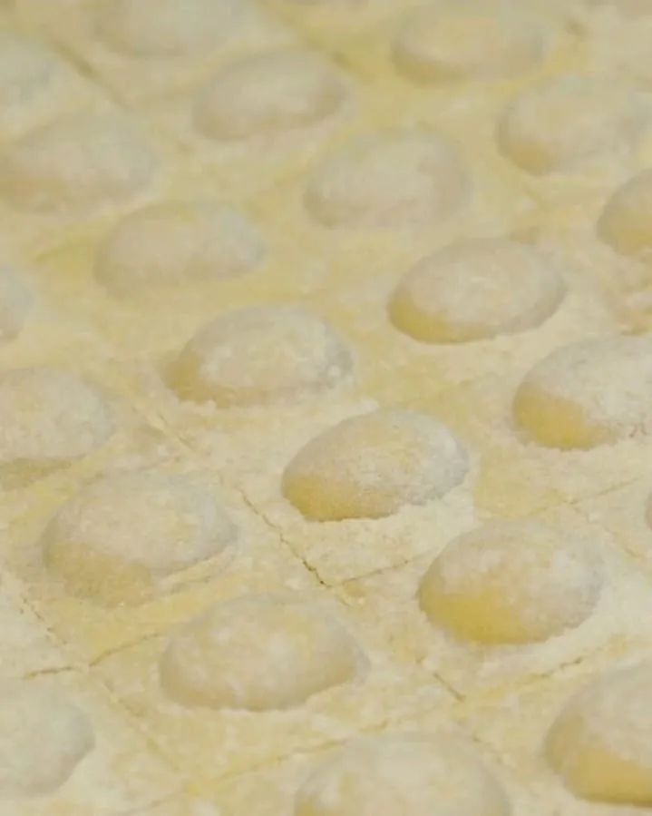 A tray of fresh ravioli dusted with flour, before service