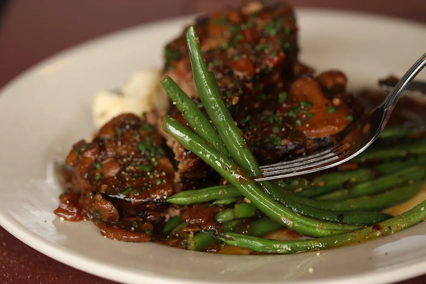 Braised beef with green beans on a white plate