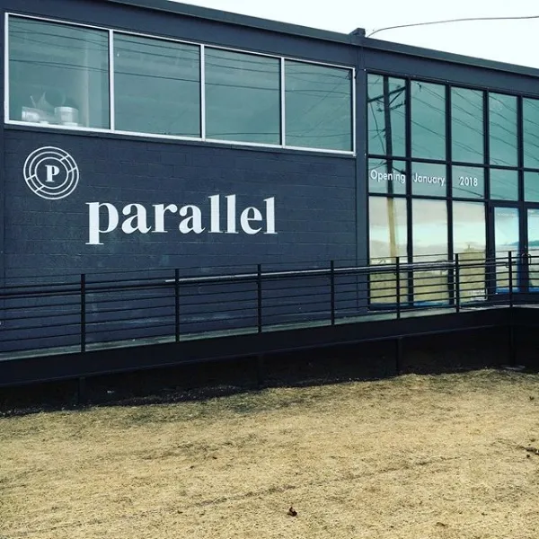 The Parallel wordmark and mark on the building’s dark exterior, under a run of high windows