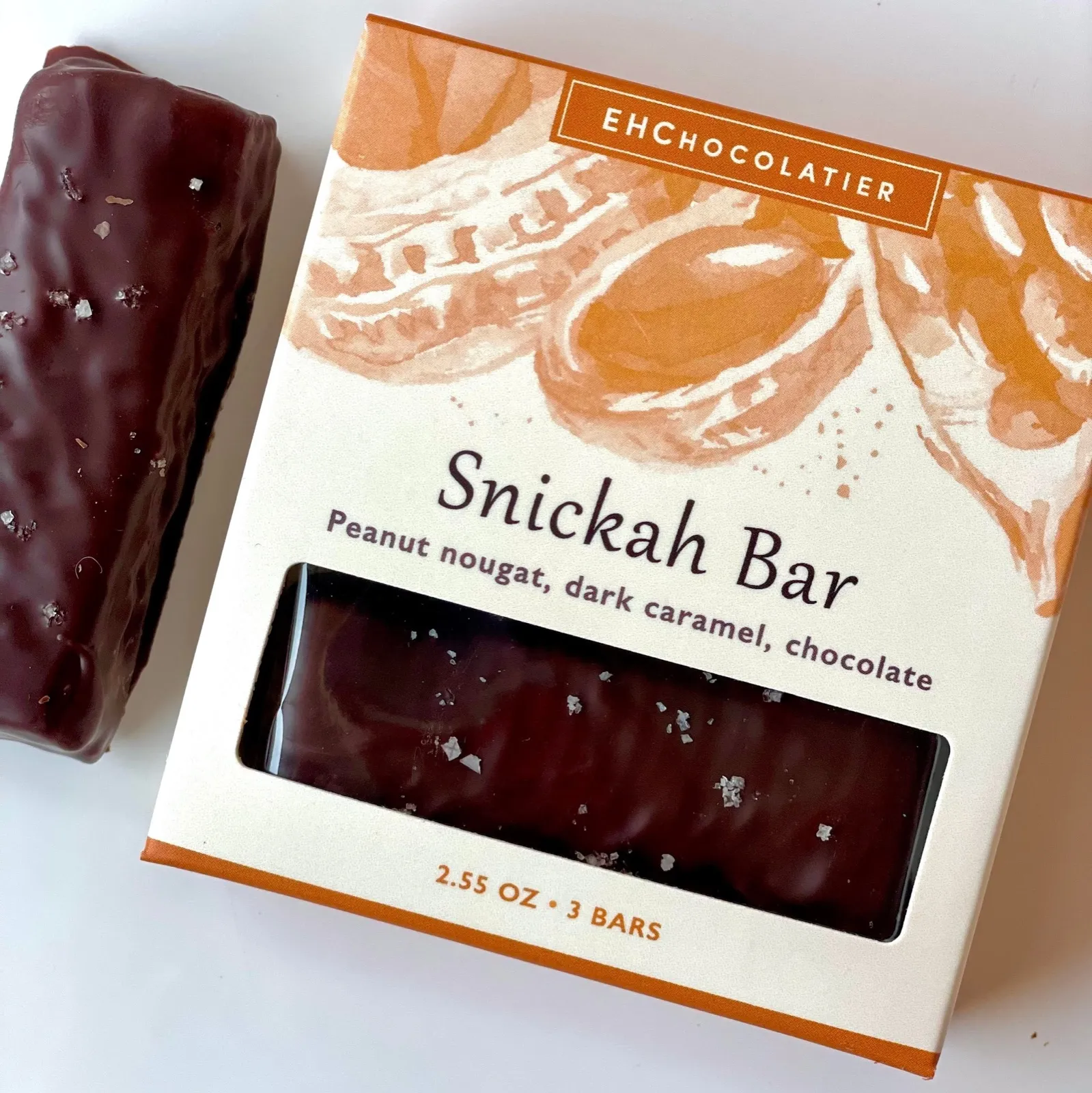 The Snickah Bar box with the bar itself beside it, the window showing the dark chocolate within