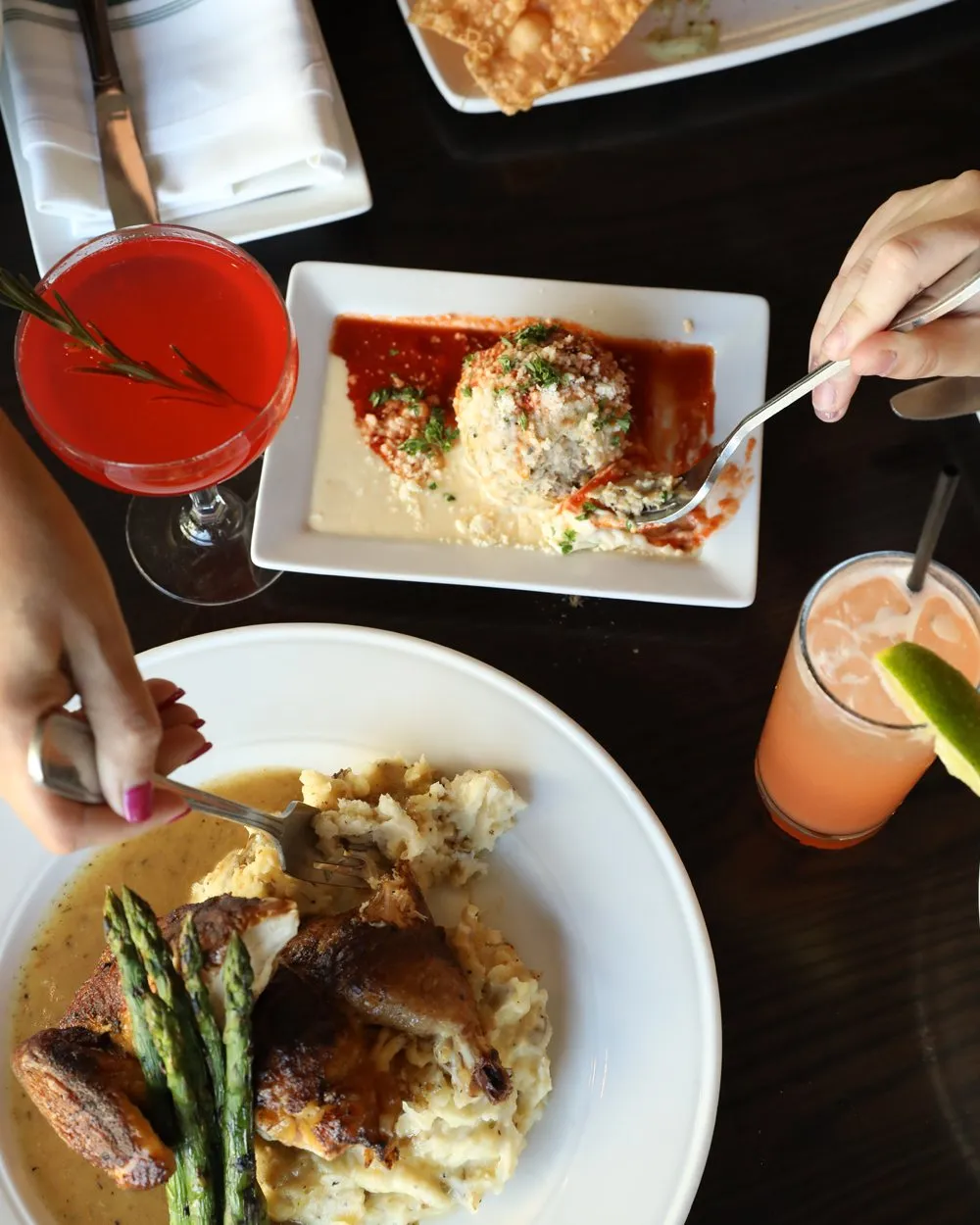 Overhead view of a Hazelwood table: entrées, a pasta dish and cocktails being shared