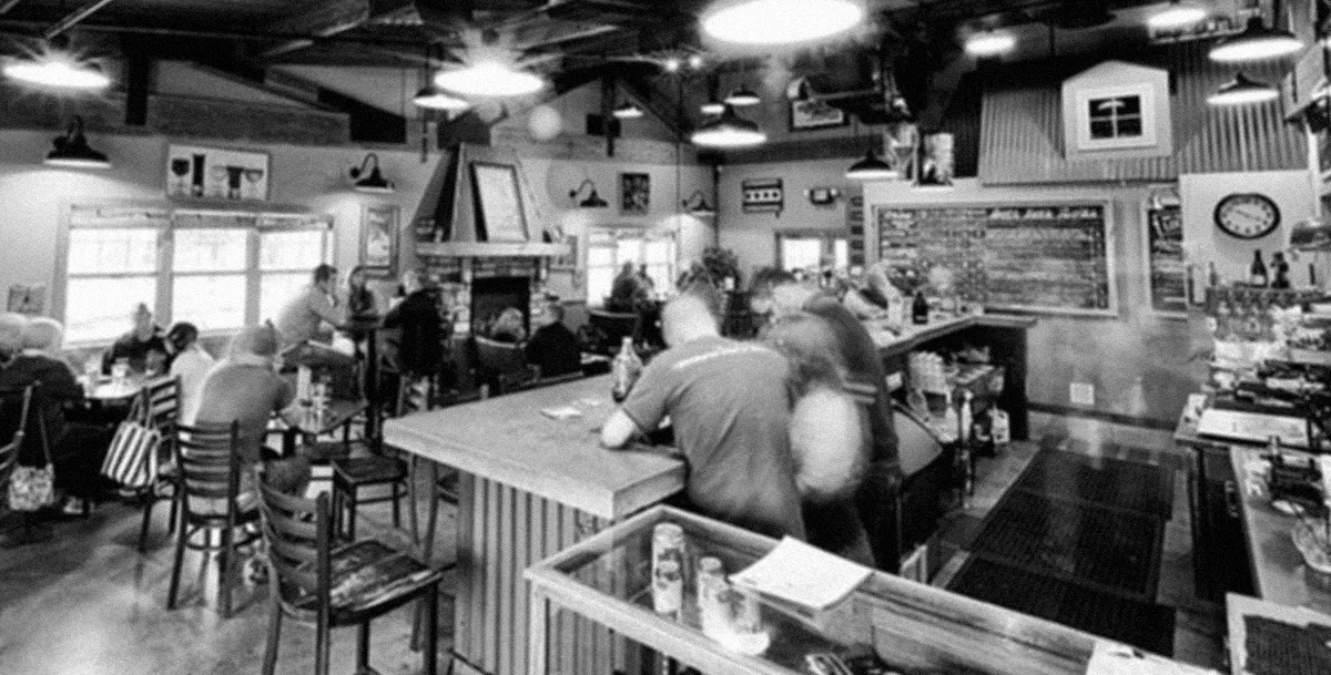 The Monument taproom, in black and white — regulars at the bar, the room busy behind them